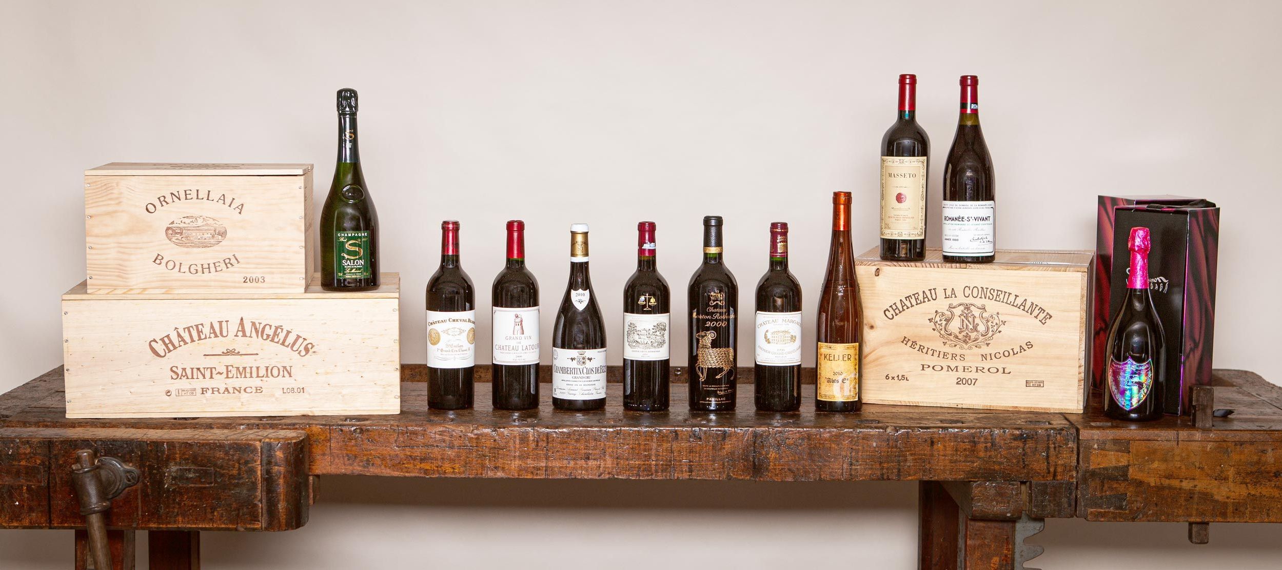 Exclusive Auswahl internationaler Spitzenweine und Champagner, arrangiert mit Holzkisten auf einem rustikalen Holztisch